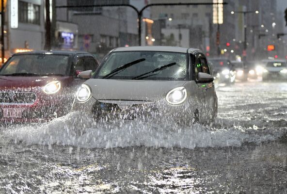激しい雨で冠水した大通りを慎重に走る乗用車＝24日午後５時15分、宇都宮市大通り４丁目