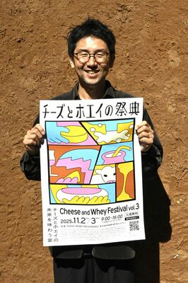 「チーズとホエイの祭典」のポスターを持つ山川実行委員長
