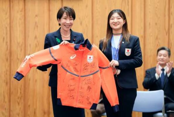 　フィギュアスケート女子の坂本花織（右）からサイン入りのウエアを贈られ笑顔の高市首相＝２４日午後、首相官邸