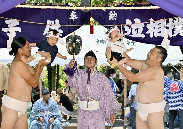 力士姿の氏子に抱えられ、元気な泣き声を響かせる子どもたち＝21日午前10時５分、鹿沼市樅山町