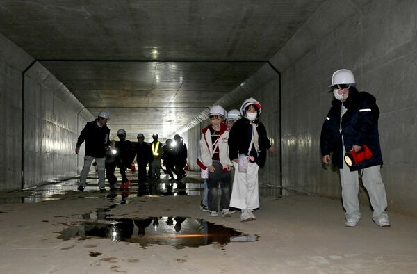 薄暗い地下河川を見学する児童たち＝16日午前10時、宇都宮市峰４丁目