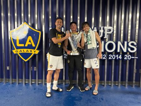 　ロサンゼルス・ギャラクシーの吉田麻也（左）、山根視来（右）とＭＬＳカップを手にする清水俊太氏＝２０２４年１２月、ロサンゼルス近郊カーソン（清水氏提供）
