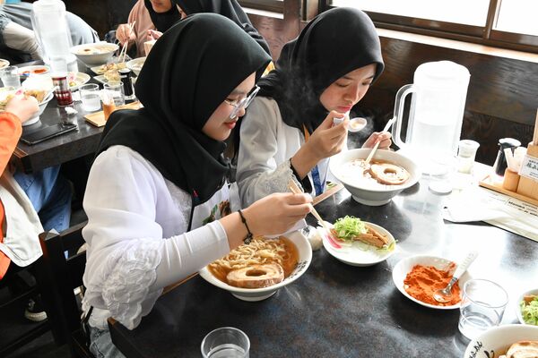 出来たてのハラルラーメンを食べるニザミア校の生徒ら