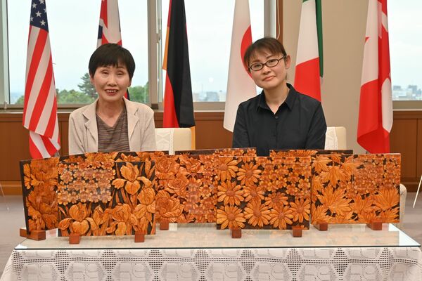 記念品となる日光彫の作品を制作した平野秀子さん（左）と央子さん＝県庁