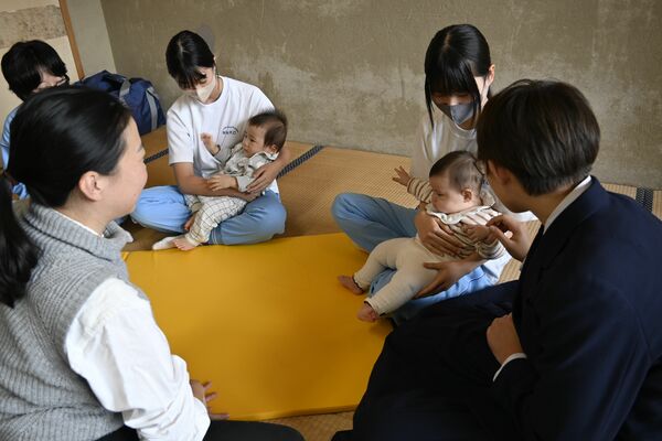 慣れない手つきで赤ちゃんを抱く中学生たち