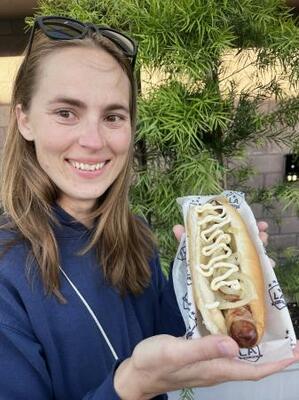 米カリフォルニア州カーソンのサッカースタジアムで、ベーコンが巻かれたソーセージのホットドッグを持つエミリー・ベッカーさん=5月(共同)