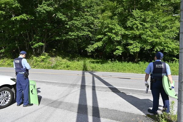 男性がクマに襲われた現場付近（写真奥）で警戒する日光署員＝１日午後３時55分、日光市足尾町砂畑