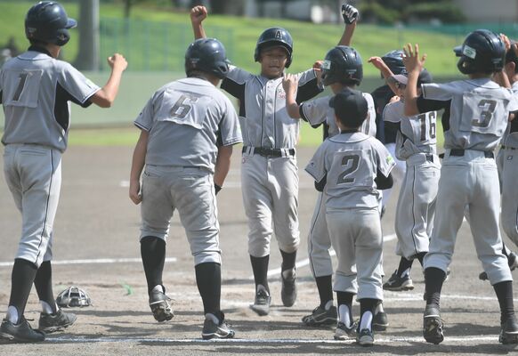 ６回、サヨナラ打を放った阿久津スポーツの八木澤（中央奥）がナインに迎えられる＝県営Ａ