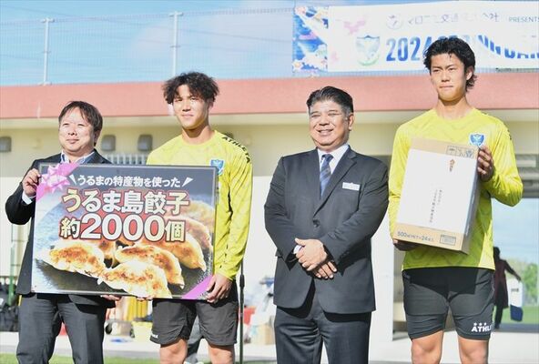 栃木ＳＣの選手に島餃子のパネルを手渡した沖縄県うるま市の松岡経済産業部長（左）