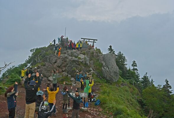 厚い雲で見えないながらも、御来光に向かって万歳する登山客たち＝１日午前４時55分、男体山山頂
