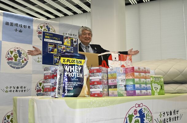 ふるさと納税の返礼品を前に笑みを見せる浅野市長