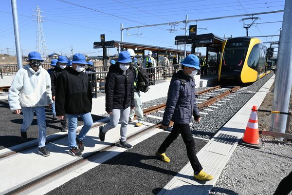 平石停留場で軌道敷を渡る児童ら
