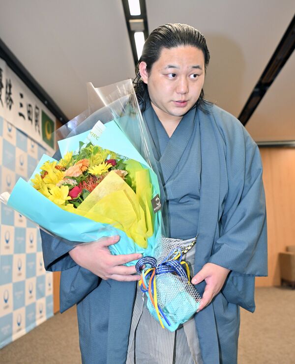 花束を手にする三田関=8日午後1時20分、大田原市本町1丁目