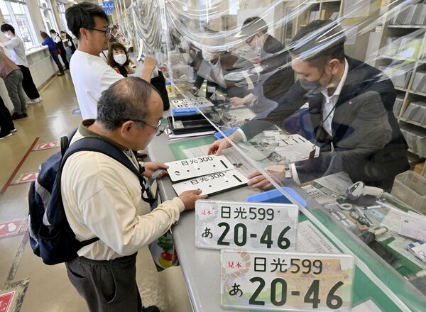 窓口で真新しい日光ナンバーを受け取る男性=7日午前10時25分、宇都宮市八千代1丁目