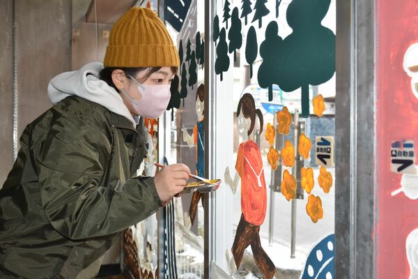 空き店舗の窓に絵を描く加藤さん