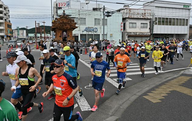 鳥居跡町の彫刻屋台のおはやしを背に走り抜けるランナーたち