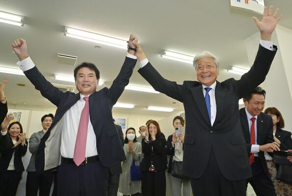 互いに６選を決めた佐藤栄一氏（左）と福田富一氏はがっちりと手を取り合い、県と市の連携を強くアピールした。20年に及んだ共同歩調はこの先の４年も継続する＝17日午後７時50分、宇都宮市不動前１丁目