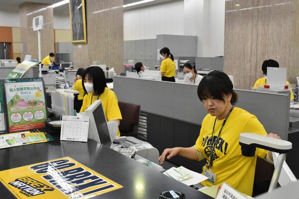 宇都宮ブレックスを応援する黄色いＴシャツを着て業務に当たる行員