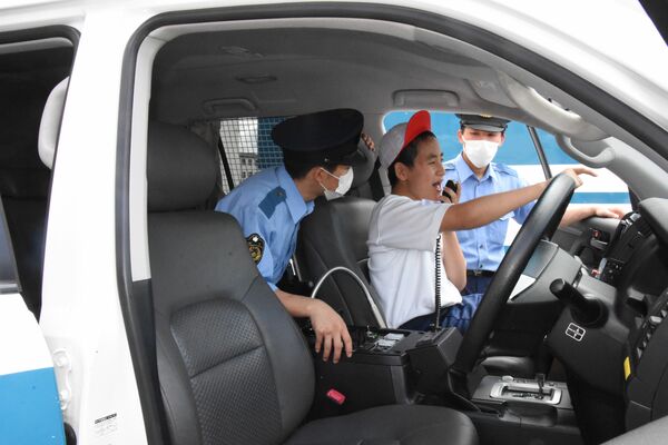 パトカーに乗って無線機の使い方を体験する生徒