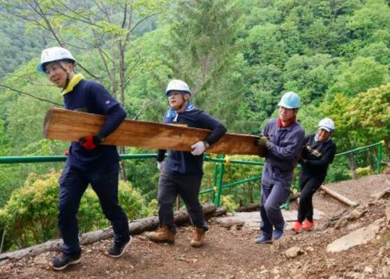 日航ジャンボ機墜落事故から41年となるのを前に、登山道整備に使う丸太を運ぶ群馬県警藤岡署の有志署員=13日午前、群馬県上野村