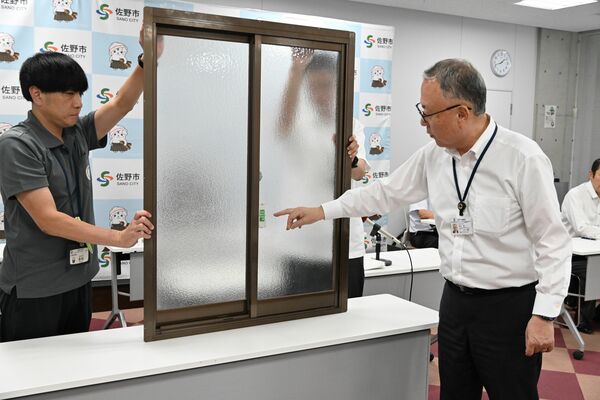 補助対象となる窓のセンサ-アラームについて説明する金子市長(右)