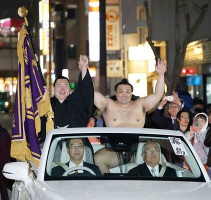 大相撲春場所で3度目の優勝を果たし、パレードで手を振る霧島。左は大青山=大阪市浪速区