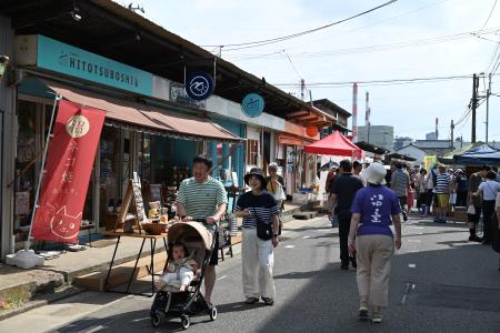 　沼垂テラス商店街で開かれた毎月の朝市イベント。通りの先に製紙工場の煙突が見える＝２０２５年７月