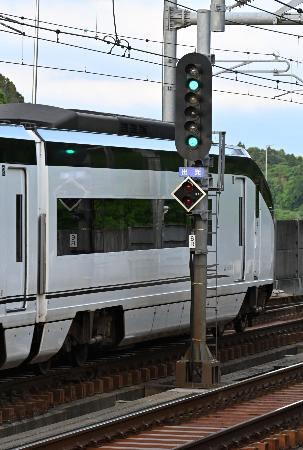 青2灯を出す信号機と通過するスカイライナー