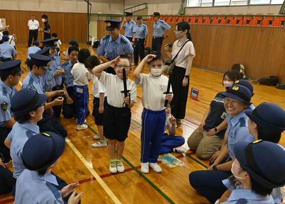 警棒を持って敬礼する児童ら