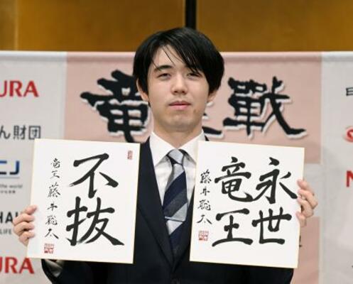 竜王戦5連覇から一夜明け、色紙を手に写真に納まる藤井聡太竜王=14日午前、京都市下京区