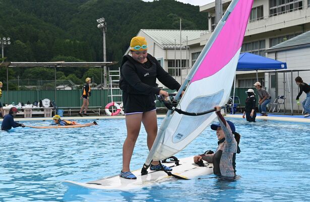 小嶺さん(右)に教わりながらウインドサーフィンに挑戦する児童