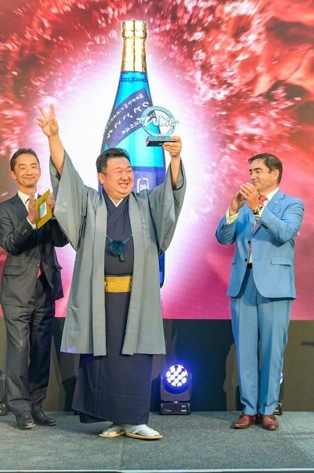 チャンピオン・サケのトロフィーを掲げる井上社長（中央）＝２０２２年７月、ロンドン（入江啓祐さん撮影）