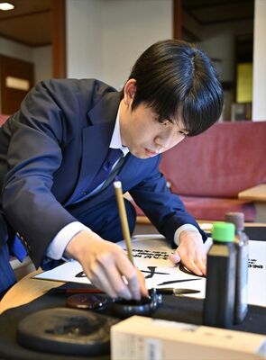 揮毫する藤井棋王＝16日午後４時25分、日光きぬ川スパホテル三日月