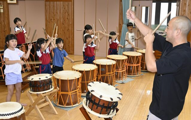 倉松園長（右）の指導で和太鼓に挑戦する日本と海外の子どもたち