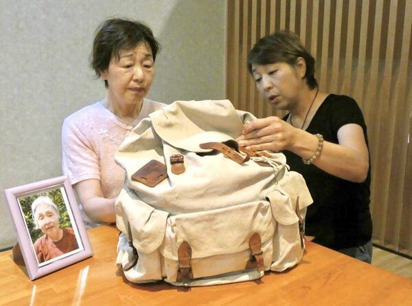伯母の周子さんのリュックを手に取る村松さん(左)と池崎さん。机上の写真は、母の和子さん=16日午後、宇都宮市