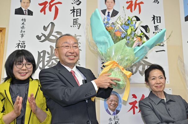 再選を果たし、花束を掲げる相馬憲一氏（中央）＝22日午後８時40分、大田原市末広３丁目、磯真奈美撮影