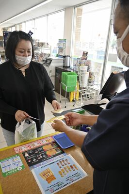 献血カードを示してファミチキレッドを受け取る協力者＝24日午後、宇都宮市越戸３丁目