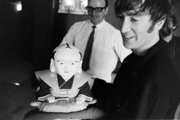 　福助人形を手にほほ笑む英ロックバンド「ビートルズ」のジョン・レノンさん。１９６６年の来日公演で撮影された写真１０２枚分のネガフィルムが見つかった（日本武道館提供）