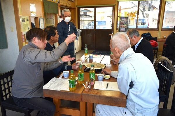試験栽培したソバの新品種を試食する関係者と説明するソバ生産者の半田さん（左から３人目）
