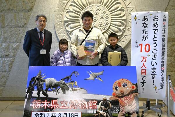 １０万人目となった清水さん親子（右から３人）＝１８日午後、県立博物館
