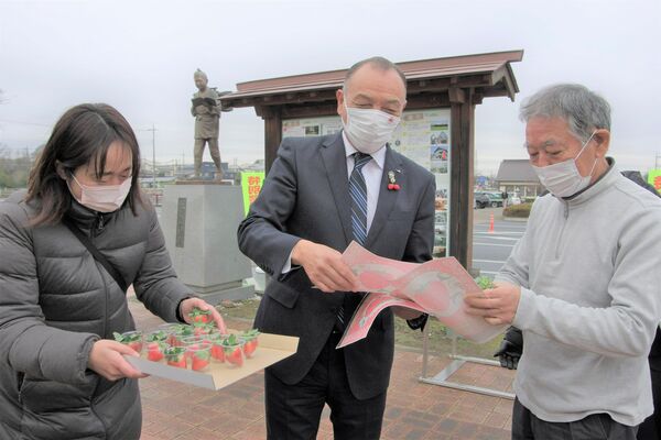 道の駅にのみやでイチゴとチラシを来場者に配る国府田組合長（中央）