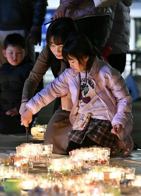キャンドルに火をともす参加者＝11日午後６時30分、宇都宮市江野町