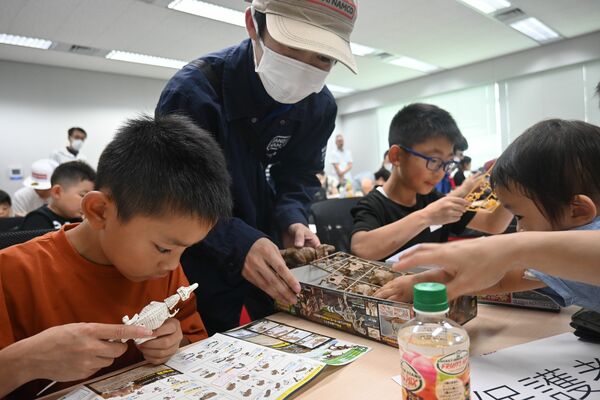 アドバイスを受けながら真剣な表情でプラモデルを作る子どもたち