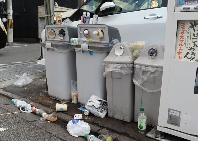中に入りきらず、リサイクルボックスの上や路上に投棄されたごみ。清掃やごみの回収は飲料メーカーが担っている場合が多い＝４月６日、京都市東山区