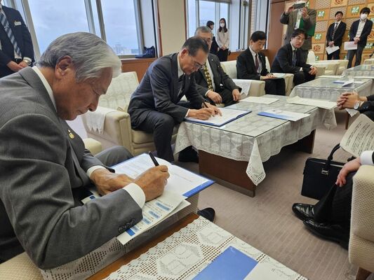 基本合意書に署名する福田知事（左）と新木理事長（左から２人目）＝26日午後、県庁