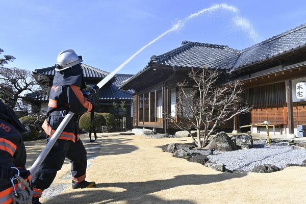 飯塚邸に向かって放水する消防署員