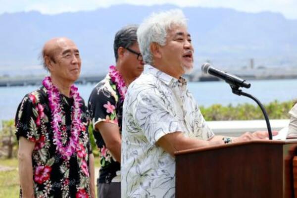 24日、米ハワイの真珠湾で開かれた式典であいさつする佐々木住幸さん。左端は雅弘さん(共同)