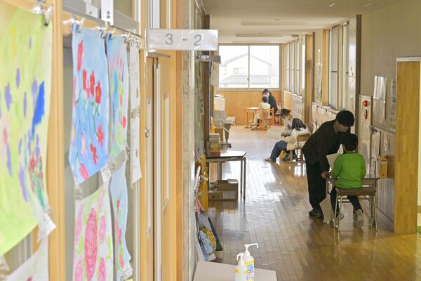 廊下で一人一人と面談し、通知表を手に２学期を振り返る各クラスの担任教諭＝25日午前11時15分、足利市福富町