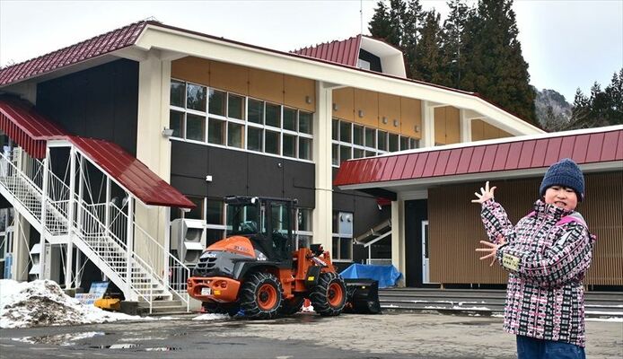 新阿仁学園となる旧阿仁合小校舎と高鳥さん。改修はされたが、外観や建物の配置は旧阿仁合小とほぼ同じだ
