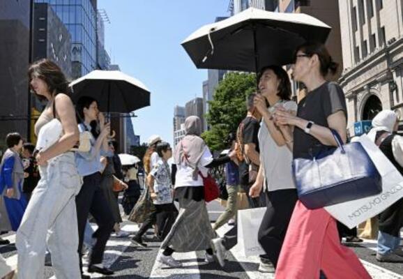日傘を差して東京・銀座を歩く人たち。都心は今年初の真夏日となった=17日